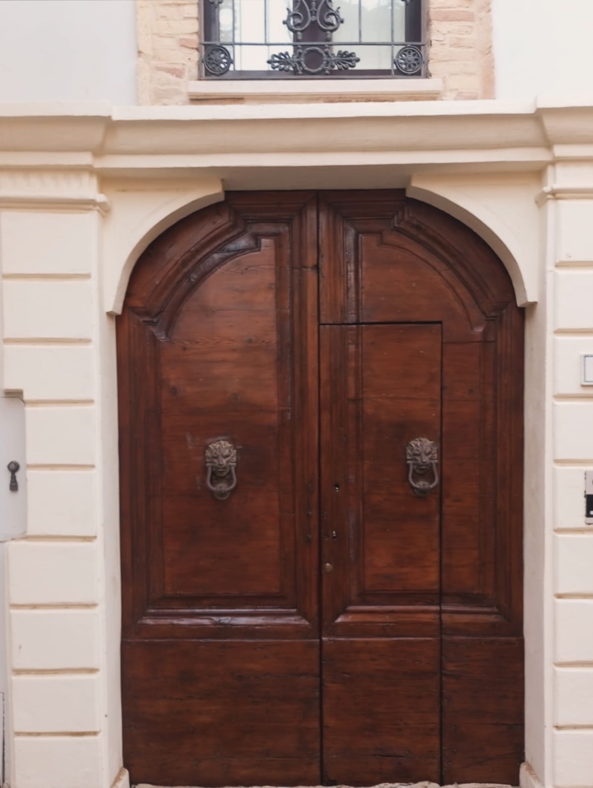 Portone in legno ad arco con battenti in ottone